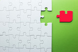 white puzzle with a red piece that does not fit on a green background