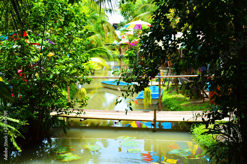 Water course in garden with wooid bridge,blue boats and colorful umbrellas photo