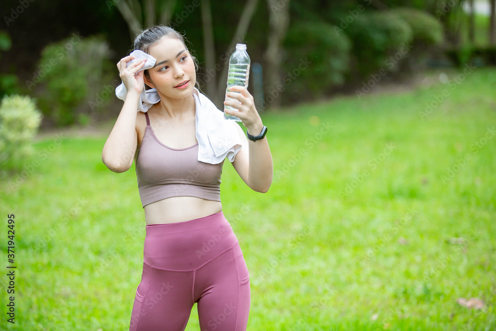A beautiful woman drinking clean water in a bottle happily after finishing exercise. A beautiful woman drinking clean water in a bottle happily after finishing exercise.