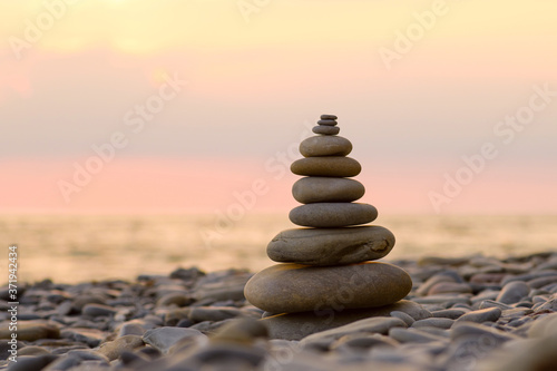 Pebbles on the beach in the form of a pyramid against the backdrop of the sea and sunset. Sunset at sea.