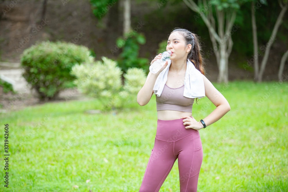 A beautiful woman drinking clean water in a bottle happily after finishing exercise. A beautiful woman drinking clean water in a bottle happily after finishing exercise.