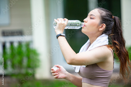 A beautiful woman drinking clean water in a bottle happily after finishing exercise.