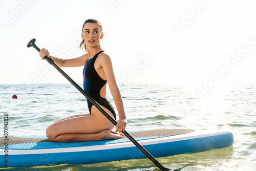 Image of focused beautiful girl in swimsuit kayaking with paddle © Drobot Dean