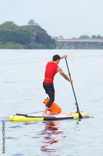 Man rowing inflatable stand up paddle board across the river