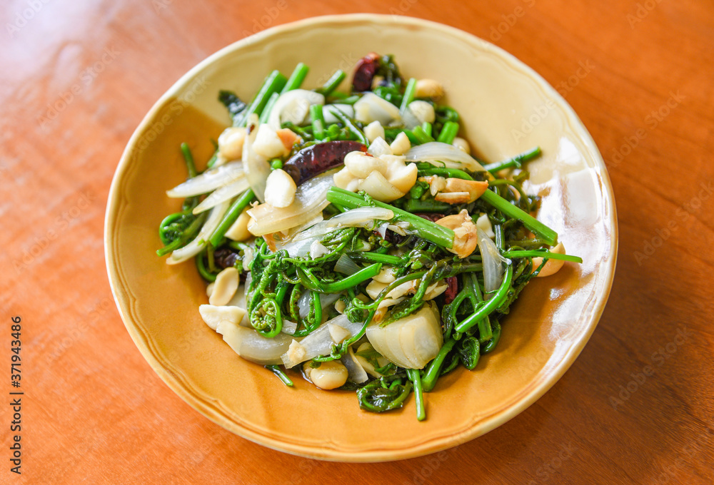 Fried vegetables - Stir fry paco fern with macadamia nuts on top on white plate , Healthy food Fried vegetables - Stir fry paco fern with macadamia nuts on top on white plate , Healthy food