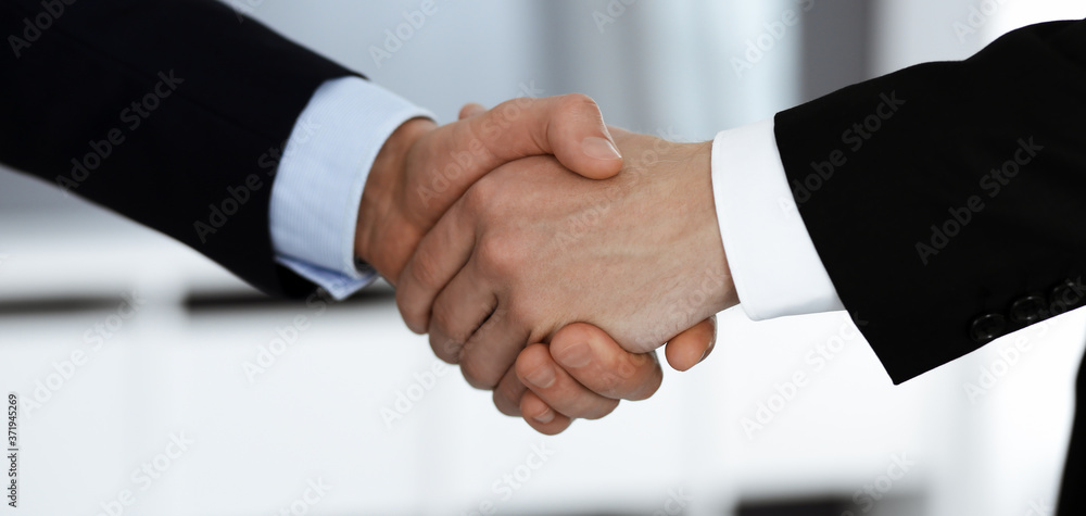 Business people shaking hands after contract signing while standing in a modern office. Teamwork and handshake concept