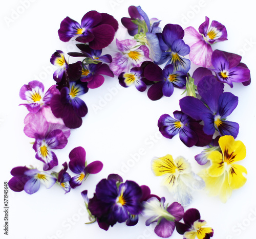 Round Frame with flowers and leaves. Top view background with pansy flowers. Flowers composition. Mock up with plants. Flat lay with flowers on white table. Woman day concept. Copyspace for text.