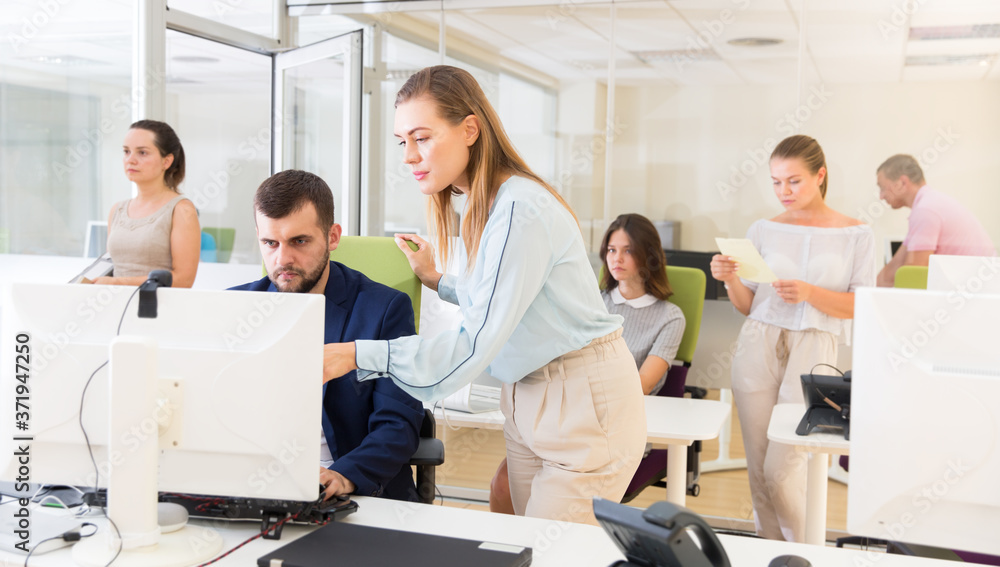 Fototapeta premium Successful businesswoman explaining something to male partner, pointing at computer monitor