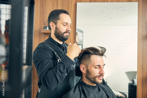 Kind bearded man working in salon with pleasure