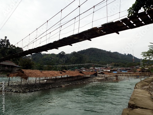 Wooden bridge over some huts and over the Bahorok river as it passes through Bukit Lawang in the North Sumatra province of Indonesia. photo