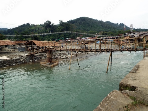 Wooden bridge over the Bahorok river as it passes through Bukit Lawang with the mountain in the background in the North Sumatra province of Indonesia. photo