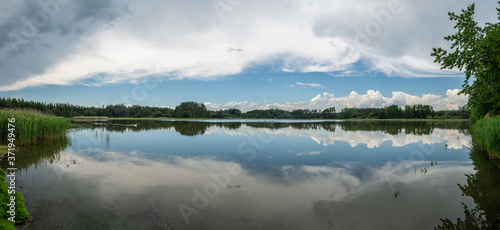 Fototapeta Naklejka Na Ścianę i Meble -  panorama mirrored blue sky with white clouds and forest in a lak