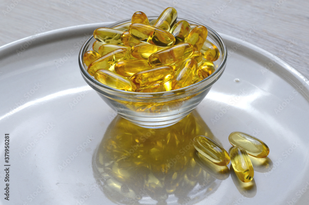 Omega-3 and Vitamin D fish oil capsules in a glass plate. Omega-3 and Vitamin D fish oil capsules in a glass plate.