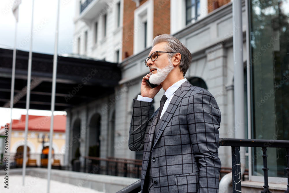 portrait of elderly senior businessman dressed in formal elegant suit talking on mobile phone portrait of elderly senior businessman dressed in formal elegant suit talking on mobile phone