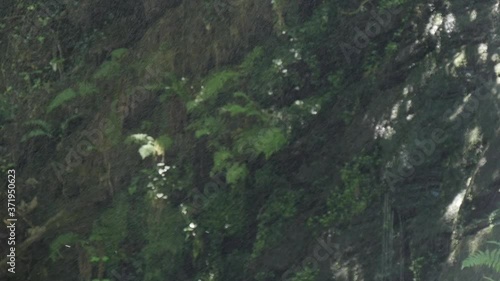 Drops of the waterfall fall, in the background you can see a wall of earth and stone. photo