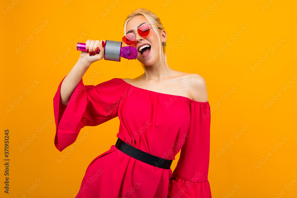 European sexy girl leading the event in a red dress with bare shoulders with a microphone in her hands European sexy girl leading the event in a red dress with bare shoulders with a microphone in her hands