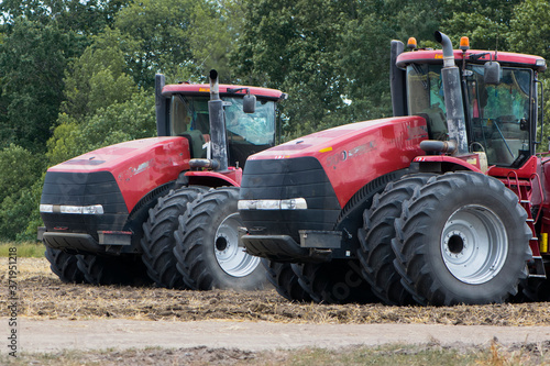  two red tractors in the field illustrative editorial