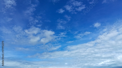 In a blue sky with light white translucent clouds, the wind is catching up to the horizon with clouds that completely cover the bright summer sky with a gray-white veil.