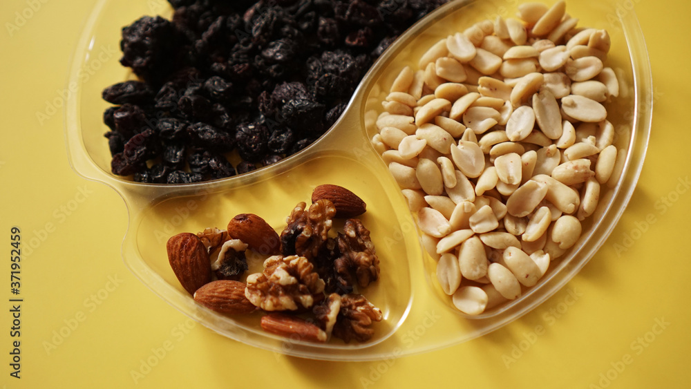 Top closeup view of delicious nuts in plastic transparent containers on yellow background