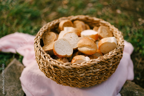 A close-up of a wicker basket filled with slices of fresh bread on a pink cloth mat.