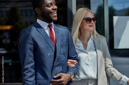 affable hotel clerk serve business client, confident and polite black man in formal wear help lady to reach the car with convenience photo