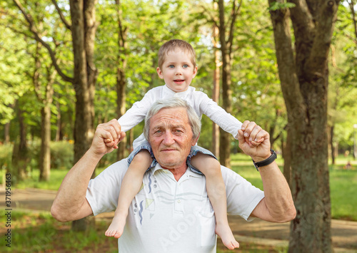 Grandfather carrying grandson on shoulders. Senior man and grandson