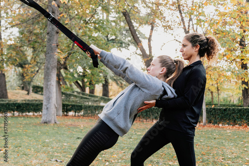 Women training with trx outside in the park.