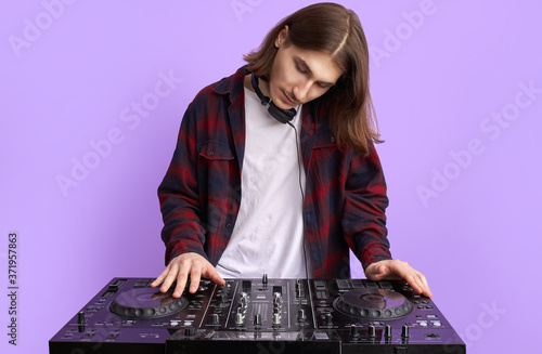 modern club DJ playing mixing music on vinyl turntable, isolated in studio. caucsaian male perform techno style music, enjoy playing on equipment photo