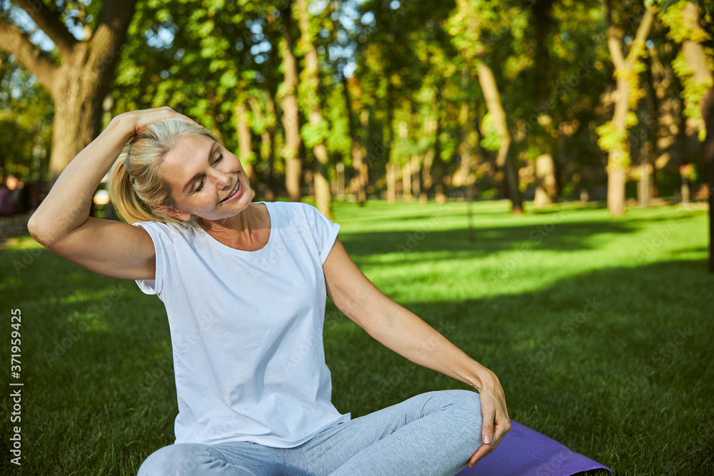 Beautiful joyful woman sitting on grass in park Beautiful joyful woman sitting on grass in park