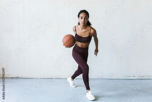 Photo of young african american sportswoman working out with basketball © Drobot Dean