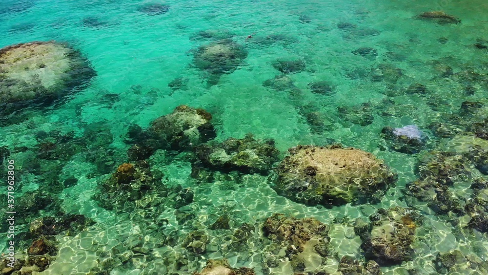 Calm sea water near stones. Peaceful blue sea water and gray boulders in perfect place for snorkeling on Koh Tao Island on sunny day in Thailand. Natural background texture.