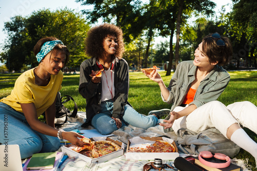 Image of funny nice student girls eating pizza while doing homework