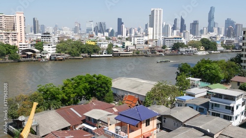 Financial district near calm river. View of skyscrapers located on shore of tranquil Chao Praya river in downtown district of Bangkok. Big city life panorama. Boats on the water in Krungthep. photo