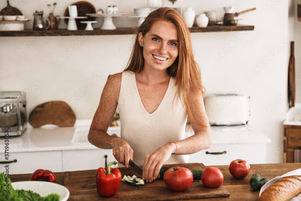 Smiling attractive young woman making a salad