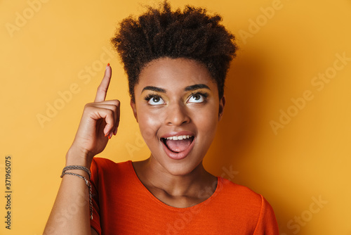 Image of african american woman pointing finger upward and smiling