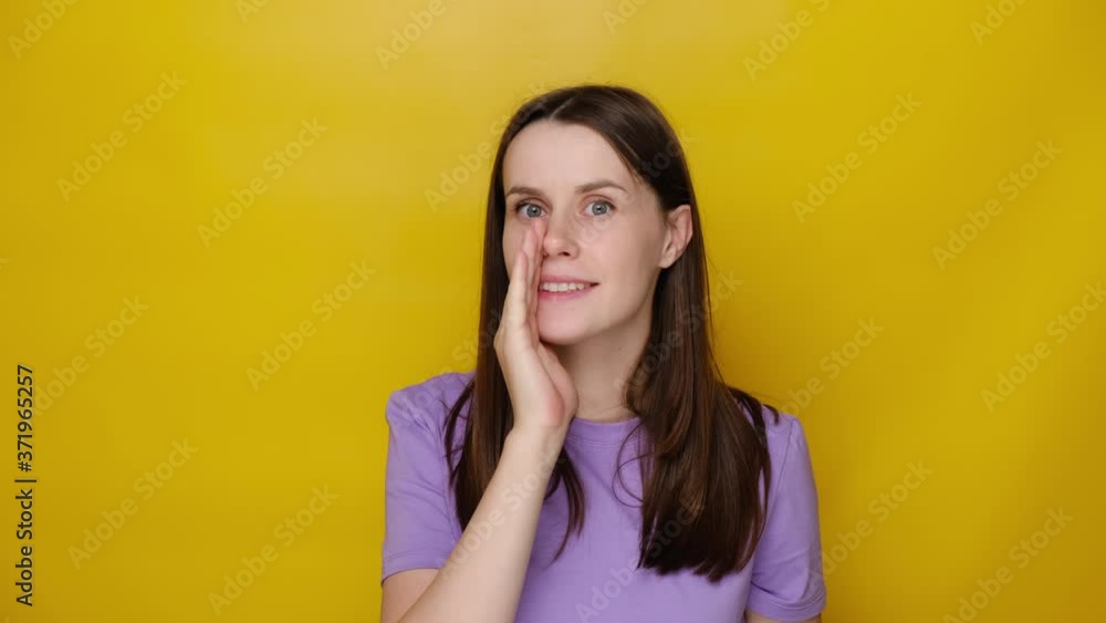 Serious young woman look at camera tell secret information, millennial cute girl make loudspeaker share private sale promotion, dressed in purple t-shirt, isolated on yellow studio background Serious young woman look at camera tell secret information, millennial cute girl make loudspeaker share private sale promotion, dressed in purple t-shirt, isolated on yellow studio background