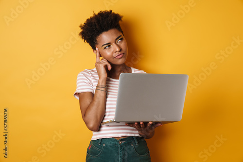 Image of serious african american woman thinking and using laptop