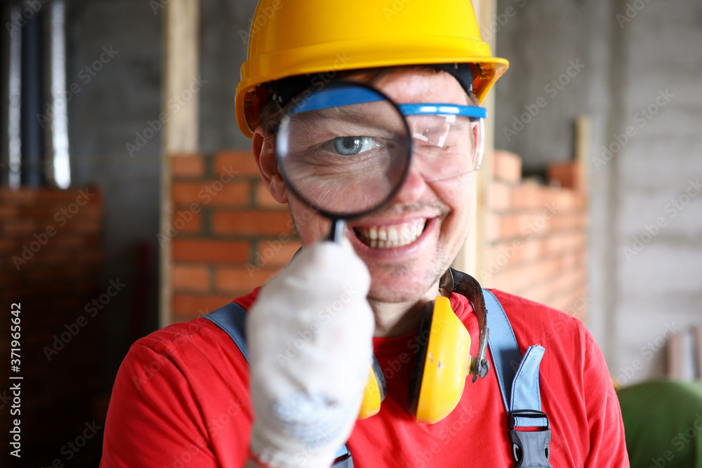 Builder looking through magnifying glass, smiling Builder looking through magnifying glass, smiling