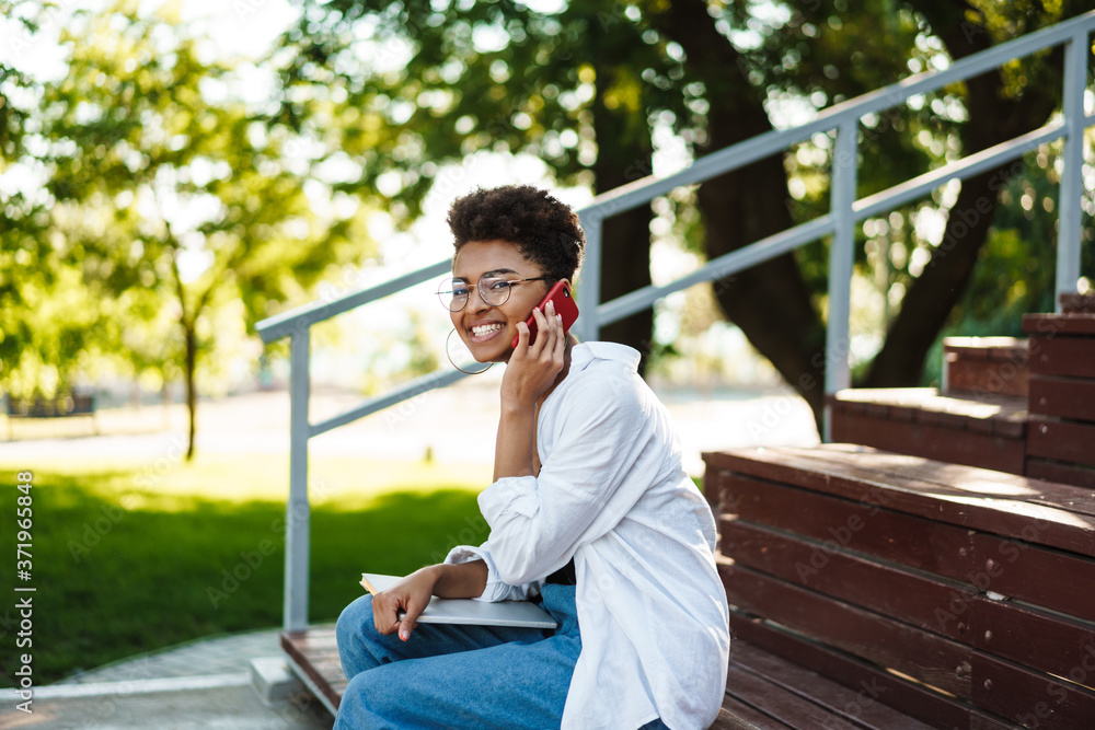 Woman sitting outdoors while talking by mobile phone