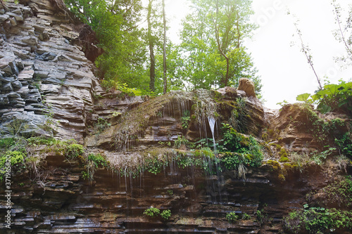 Rocks with a flowing streams of the mountain creek in morning sunlight.