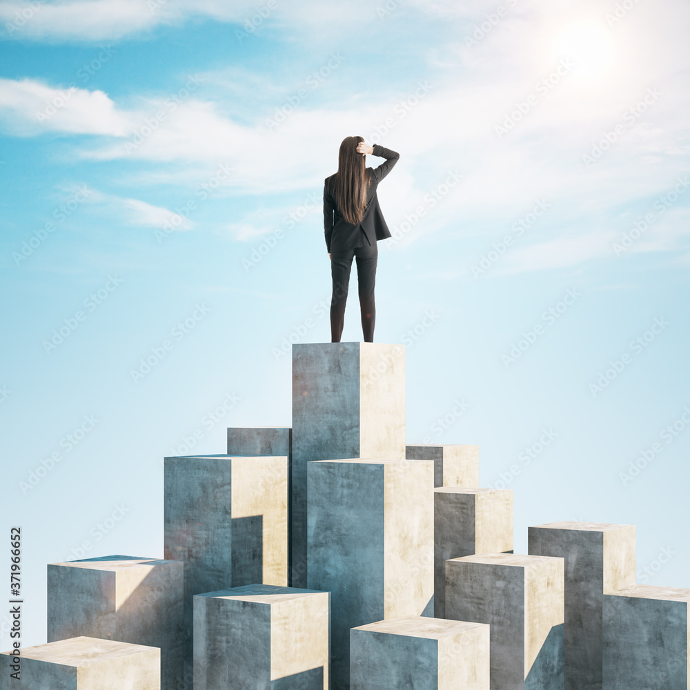 Businesswoman standing on concrete cube and look into distance.