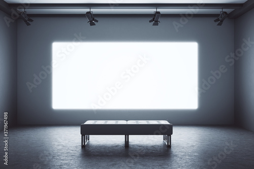 Exhibition interior with empty projection screen and bench.