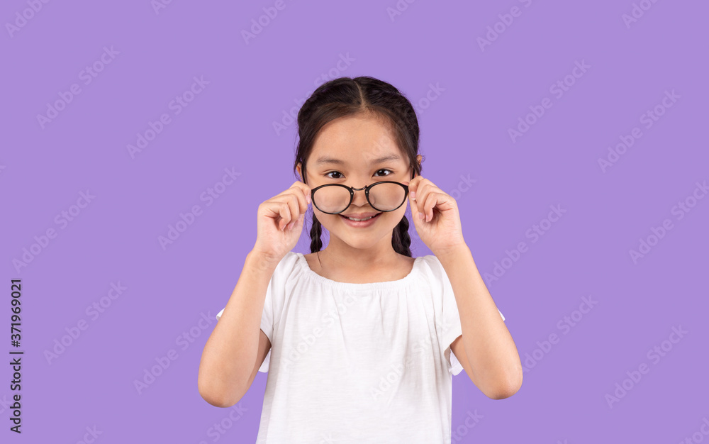 Asian Little Girl Looking At Camera Above Glasses, Studio Shot Asian Little Girl Looking At Camera Above Glasses, Studio Shot