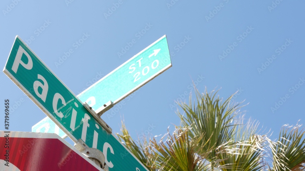 Fototapeta premium Pacific street road sign on crossroad, route 101 tourist destination, California, USA. Lettering on intersection signpost, symbol of summertime travel and vacations.Signboard in city near Los Angeles
