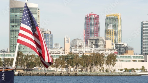 Metropolis urban skyline, highrise skyscrapers of city downtown, San Diego Bay, California USA. Waterfront buildings near pacific ocean harbour. Star-Spangled Banner, Old Glory national flag waving