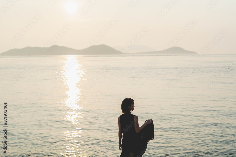 夕陽の海にいる女性