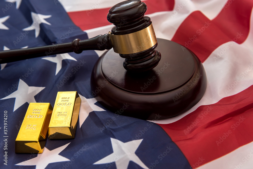 gold bars with justice law hammer lying on usa flag