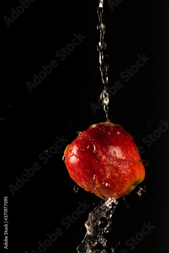 Apple with beautiful splash of water with black background and selective focus.