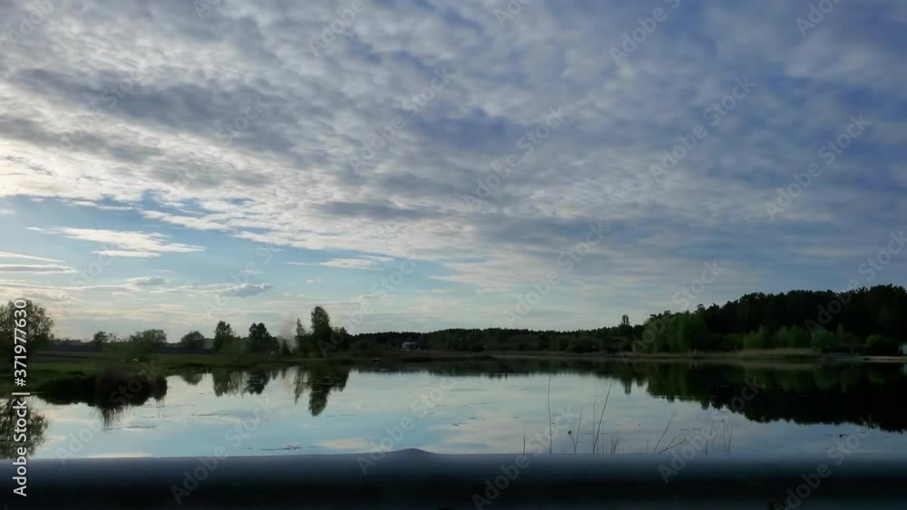 Moving scenery seen through the windows of vehicle, mirror-smooth lake reflecting sky, countryside, rural Moving scenery seen through the windows of vehicle, mirror-smooth lake reflecting sky, countryside, rural