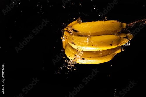 Bananas with a beautiful splash of water with black background and selective focus.